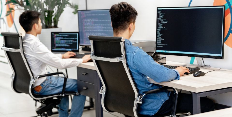 deux employés qui travaillent assis devant un ordinateur - Optimiser sa Posture de Travail au Bureau